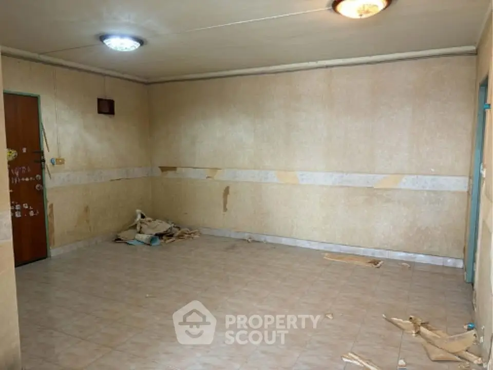 Spacious empty room with tiled floor and simple lighting, ready for renovation.