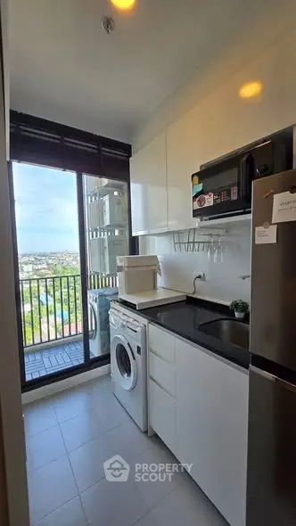 Modern kitchen with balcony view, featuring washing machine and sleek appliances.