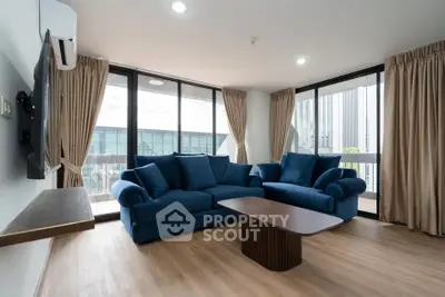 Spacious living room with modern blue sofas and large windows offering natural light.