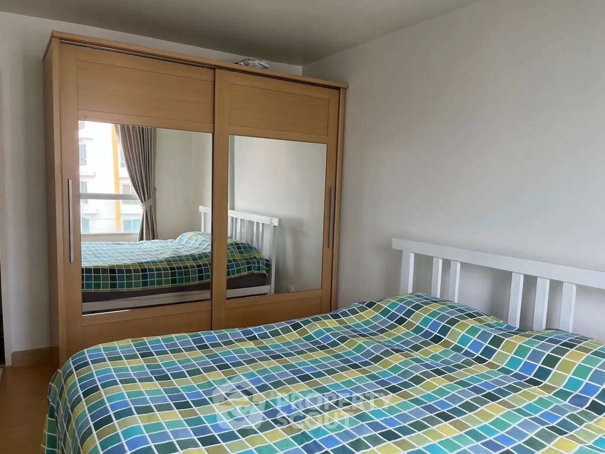 Cozy bedroom with mirrored wardrobe and colorful bedding in modern apartment.