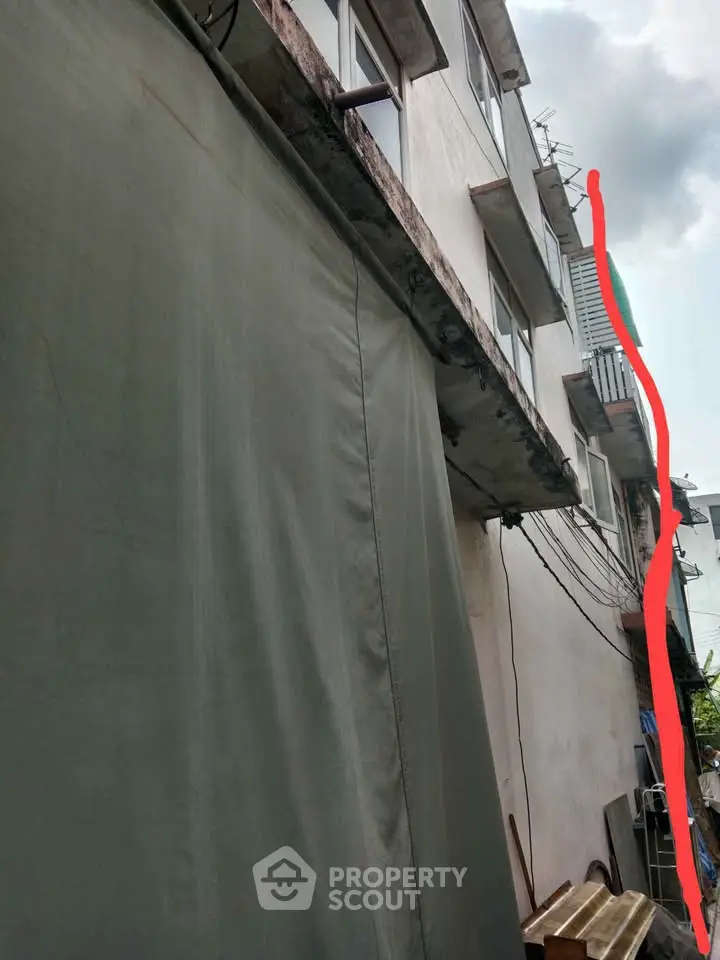 Urban building exterior with visible balconies and utility lines