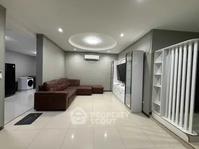 Spacious modern living room with sleek design and open layout, featuring a large brown sectional sofa and wall-mounted TV.