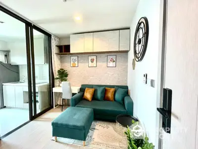 Chic modern living room with plush teal sofa, stylish wall art, and an open layout leading to a sleek kitchen, perfect for urban living.