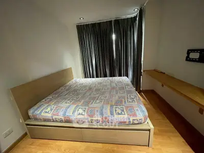 Cozy bedroom with wooden flooring and large window, featuring a comfortable bed and modern design.