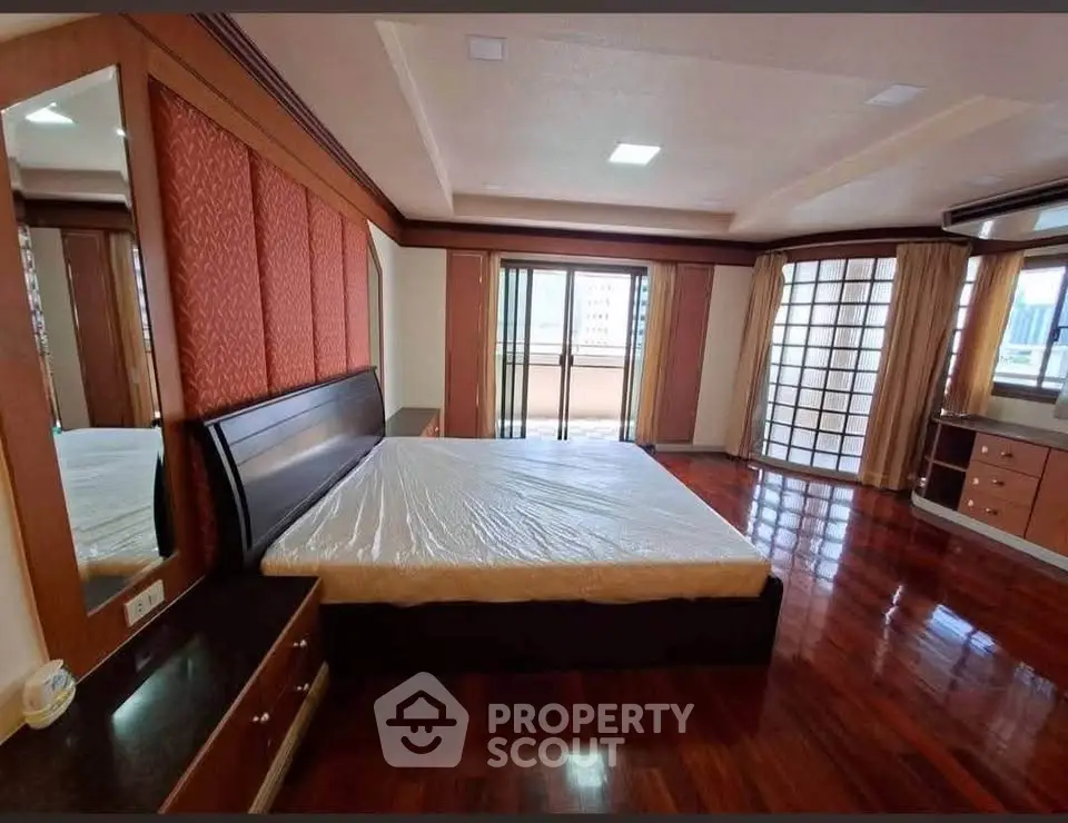 Spacious bedroom with elegant wooden flooring and large windows for natural light.