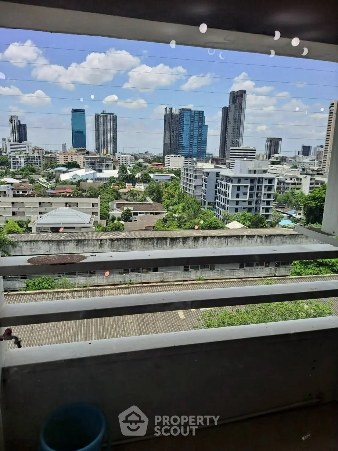 Stunning cityscape view from high-rise balcony with lush greenery and modern skyline.