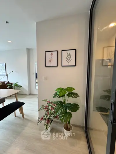 Modern living room with stylish decor and indoor plants, featuring framed botanical art on the wall.