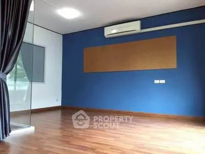 Spacious empty room with wooden flooring and blue accent wall, ideal for customization.