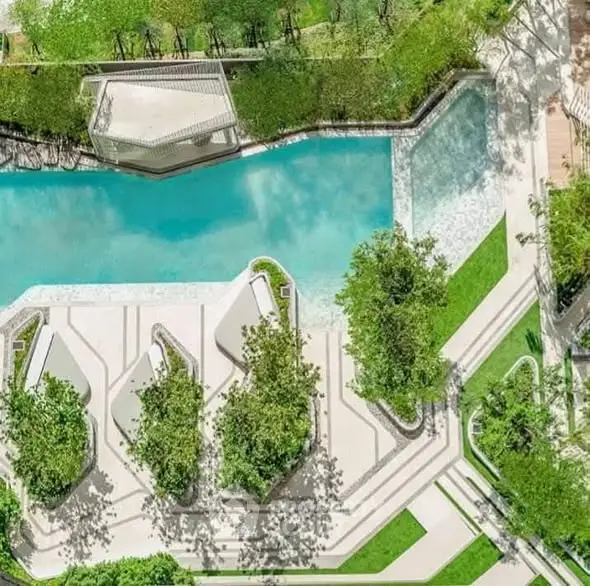 Stunning aerial view of luxurious pool surrounded by lush greenery in modern residential complex.