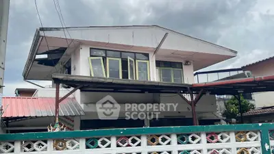 Unique two-story house with distinctive architecture and large windows, perfect for renovation or investment.