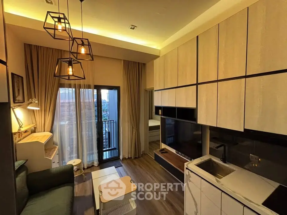 Modern living room with stylish lighting and compact kitchen in open layout apartment.