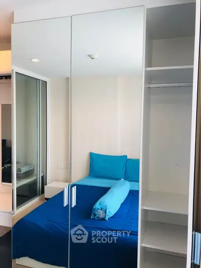 Modern bedroom with mirrored wardrobe and blue bedding in a stylish apartment.