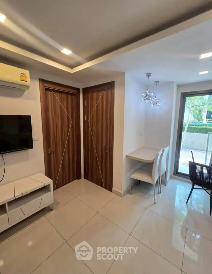 Modern living room with sleek design, featuring a wall-mounted TV, stylish lighting, and a view of the garden.
