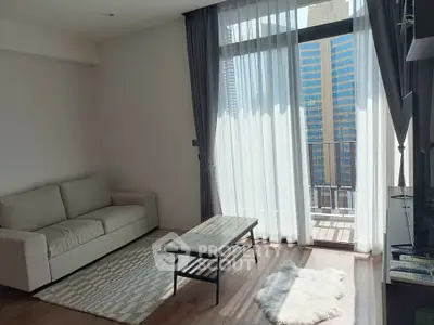 Modern living room with large window and city view, featuring a cozy sofa and stylish decor.