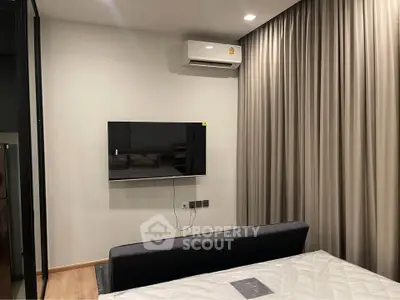 Modern bedroom with wall-mounted TV and air conditioning, featuring sleek curtains and minimalist decor.
