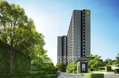 Modern high-rise building with lush greenery and clear blue sky.