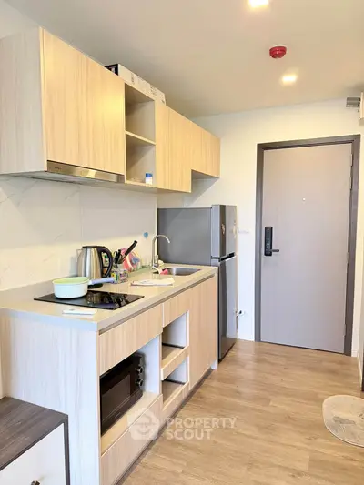 Modern kitchen with sleek wooden cabinets and stainless steel appliances in a cozy apartment.