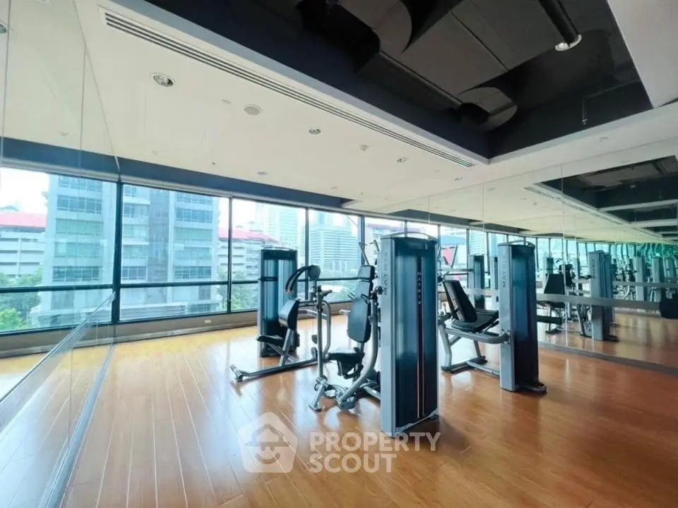 Spacious gym with modern equipment and city view in luxury building