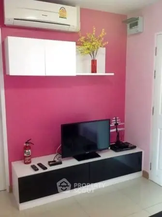 Modern living room with vibrant pink accent wall, sleek TV unit, and air conditioning.