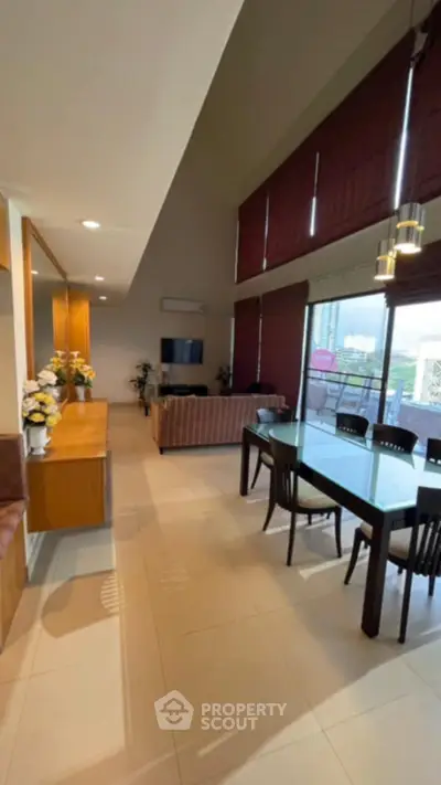 Spacious living and dining area with modern decor and large windows.