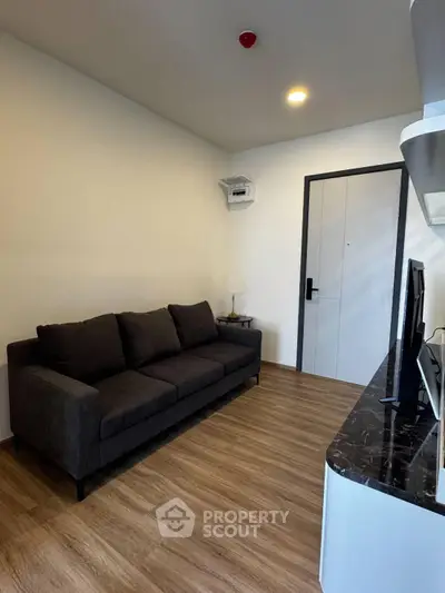 Modern living room with sleek black sofa and stylish TV unit, featuring elegant wooden flooring and minimalist decor.