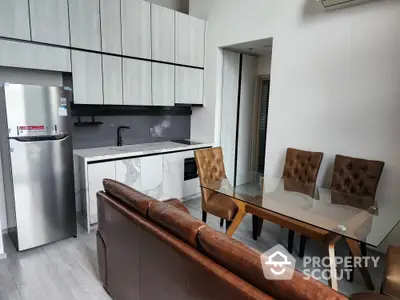 Modern kitchen with sleek white cabinetry and stainless steel appliances, adjacent to a cozy dining area with stylish chairs and a wooden table.