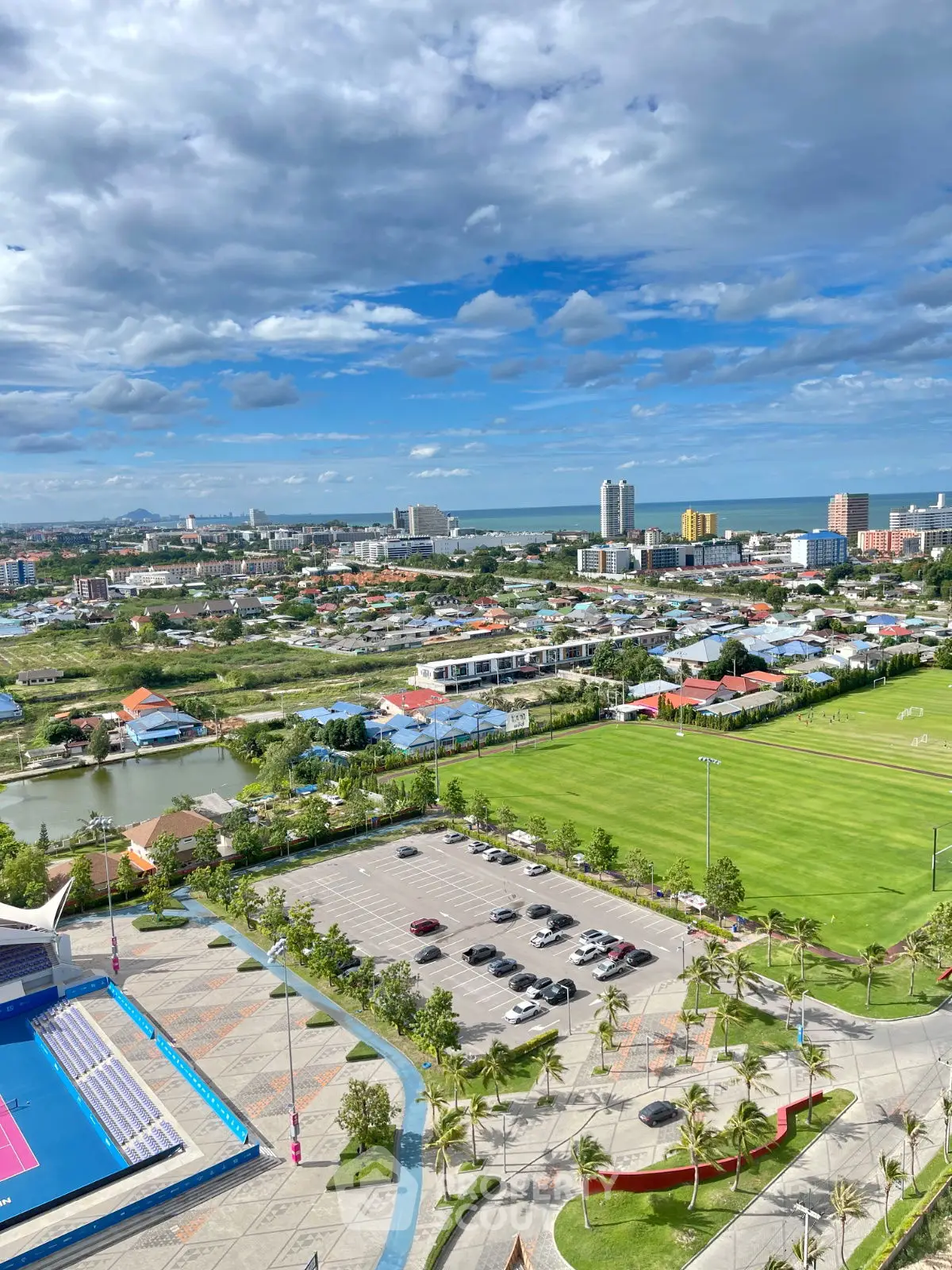 Stunning aerial view of urban landscape with lush greenery and distant ocean horizon.