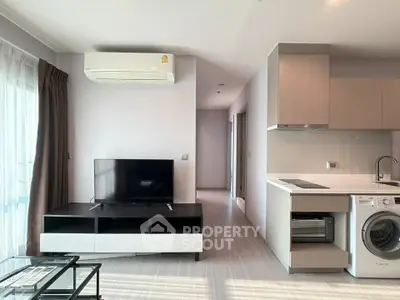 Modern living room with sleek kitchen and washing machine, perfect for urban living.
