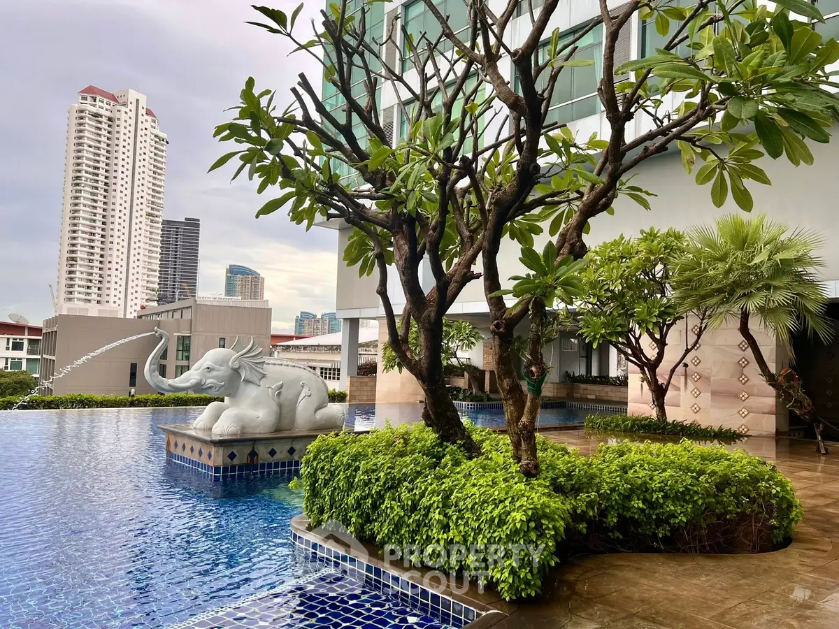 Luxurious rooftop pool with lush greenery and city skyline views, featuring elegant elephant statue.