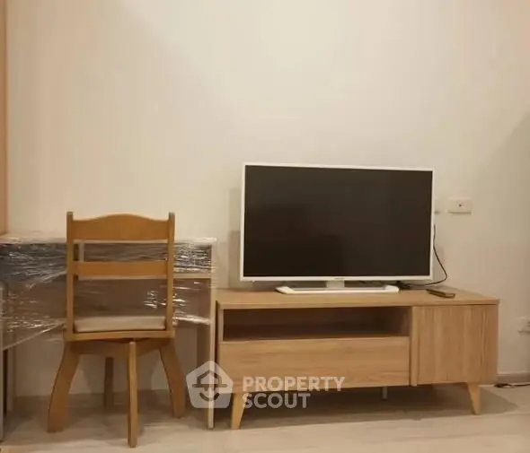 Modern living room setup with TV on wooden stand and chair beside desk.