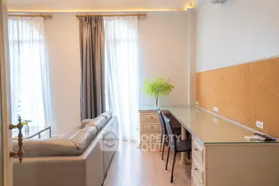 Bright living room with elegant sofa and study desk, featuring large windows and stylish curtains.