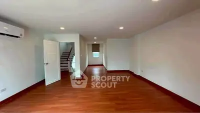 Spacious empty room with wooden flooring and air conditioning, ideal for customization.