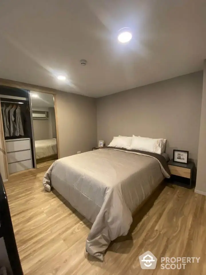 Cozy modern bedroom with wooden flooring and mirrored wardrobe