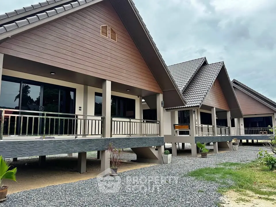 Charming row of modern A-frame houses with elevated porches and gravel pathways.