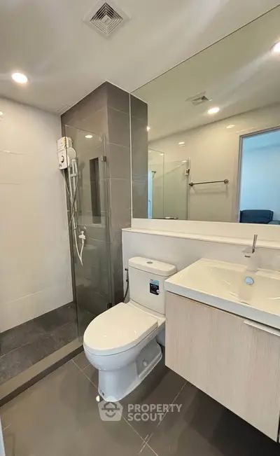 Modern bathroom with sleek design, featuring a glass shower and contemporary fixtures.