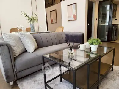 Modern living room with stylish gray sofa and glass coffee table in elegant apartment.