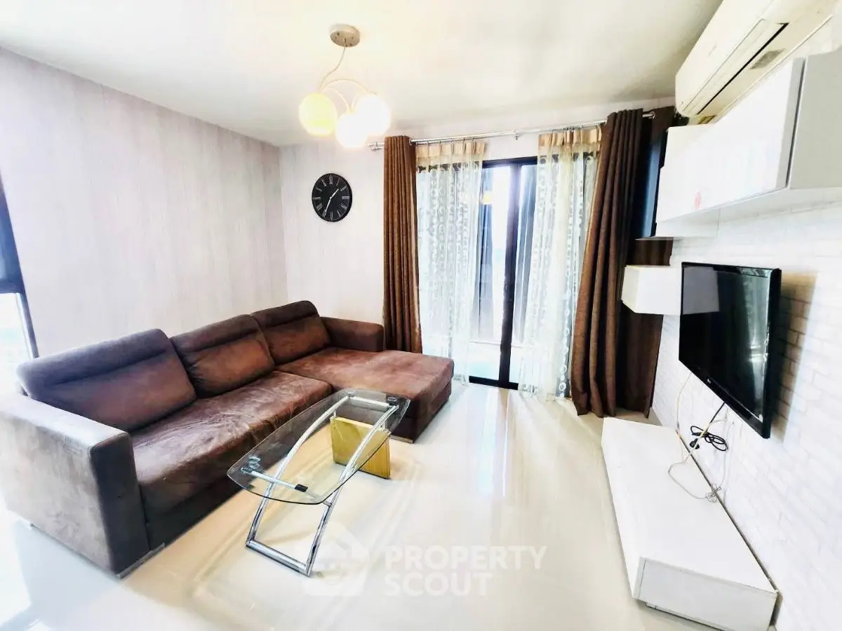 Modern living room with sleek furniture and natural light, featuring a cozy brown sofa and stylish glass coffee table.