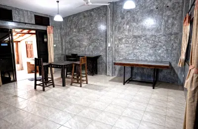 Spacious living room with modern concrete walls and tiled flooring, featuring minimalist furniture and ample natural light.
