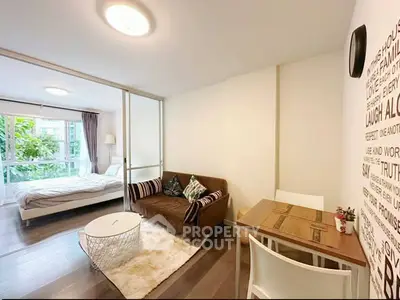 Chic studio apartment with cozy living area and modern decor, featuring a large window with a lush garden view.