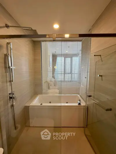 Luxurious bathroom with modern bathtub and glass shower enclosure in elegant apartment.