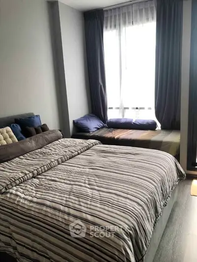 Cozy bedroom with striped bedding and large window seating area.