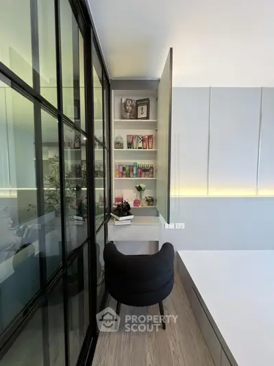 Modern study nook with sleek glass partition and stylish chair in contemporary apartment.