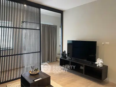 Modern living room with sleek TV stand and decorative accents, featuring a stylish partition and natural light.
