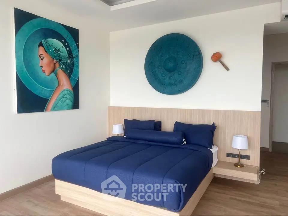 Modern bedroom with stylish decor and blue bedding in a contemporary apartment.
