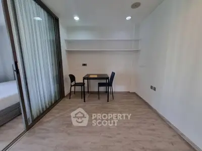 Modern minimalist study room with sleek table and chairs, adjacent to a cozy bedroom, ideal for productivity.