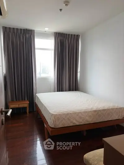 Spacious bedroom with large window and elegant curtains in modern apartment.