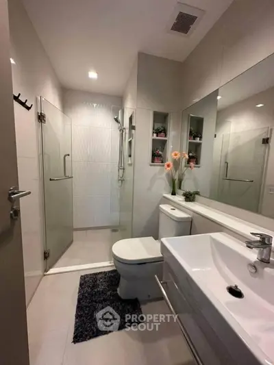 Modern bathroom with glass shower, sleek fixtures, and elegant decor.