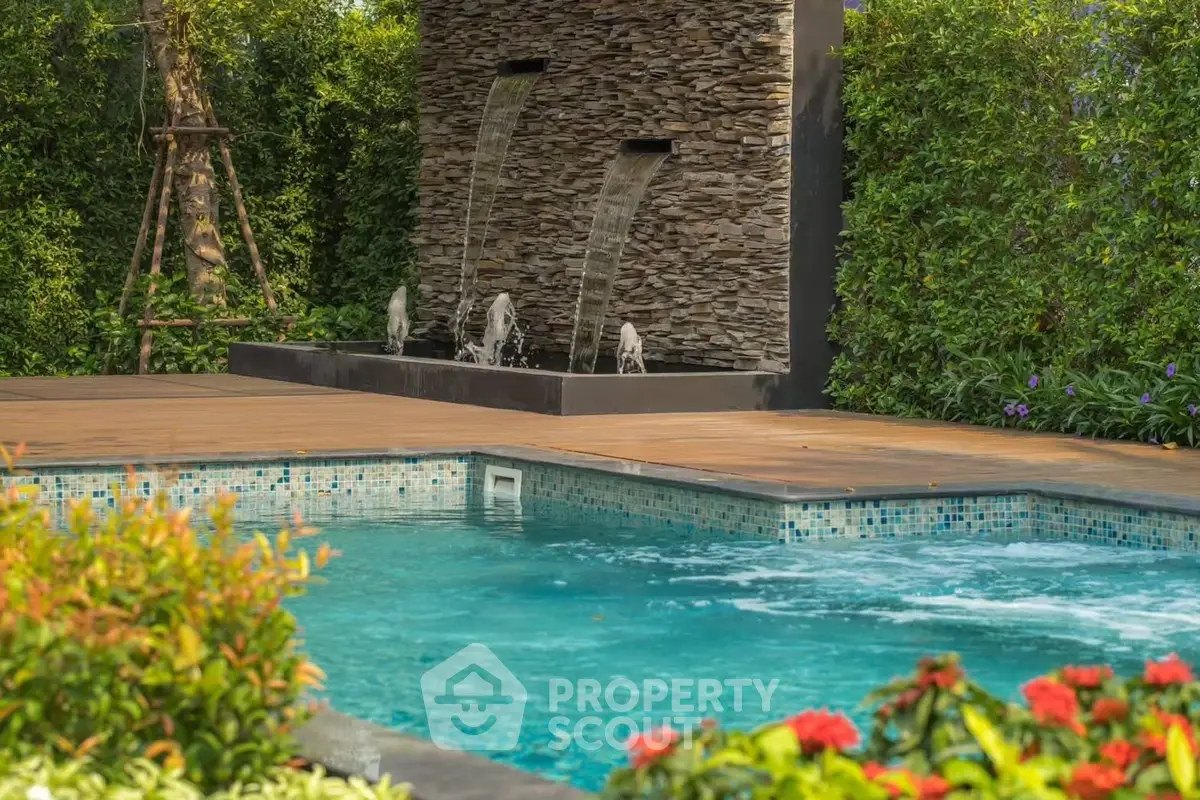 Luxurious private pool with elegant stone water feature and lush greenery.
