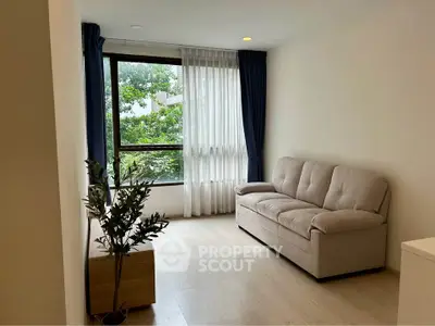 Bright living room with large window and cozy sofa, perfect for relaxation.