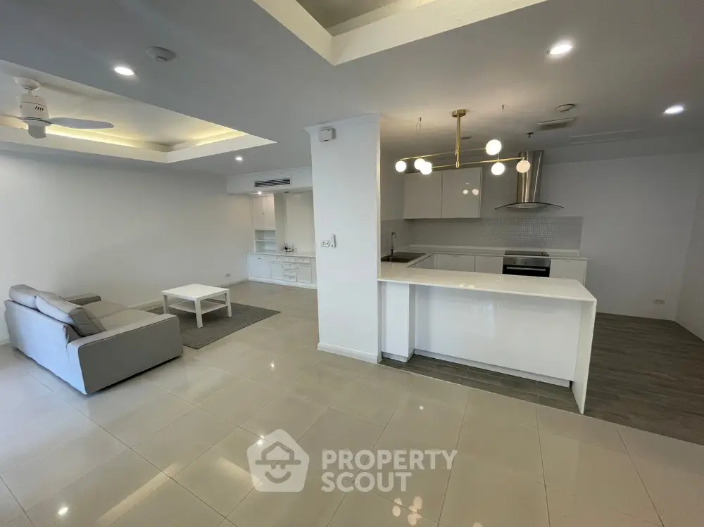 Spacious open-plan living room with modern kitchen and elegant lighting